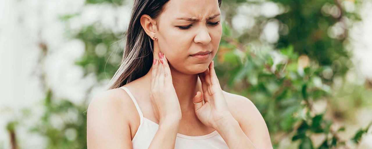 Millennial woman touching her throat in pain