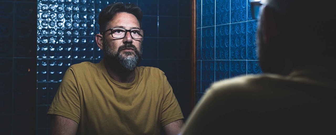 Portrait of a sad middle aged man in the mirror